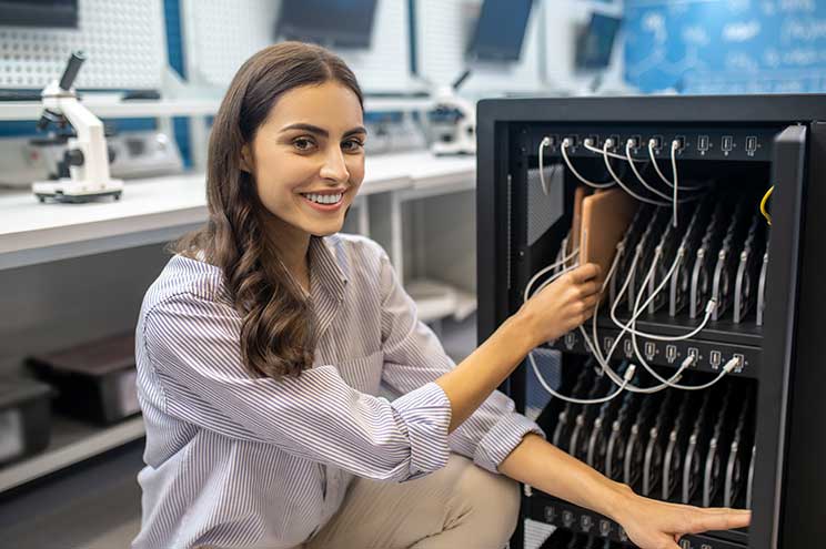 Mujer ejecutiva inspeccionando una caja de conectores de red, destacando el uso de jacks RJ45 en entornos empresariales para garantizar una conectividad eficiente y segura en redes informáticas.